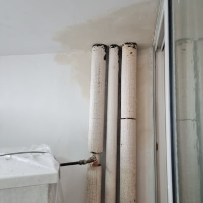 צינורות ישנים עם צבע מתקלף על קיר לבן