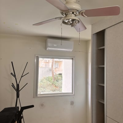 מזגן מותקן על קיר מעל חלון בחדר