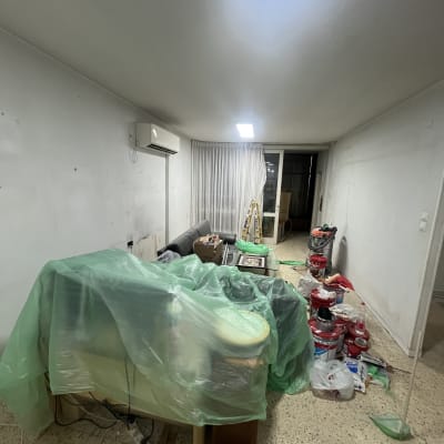 חדר עם ציוד לצביעה, כיסויים וציוד על הרצפה