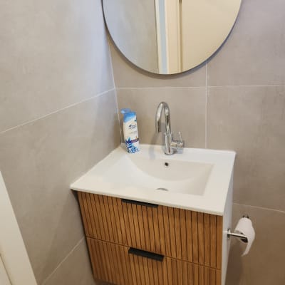 כיור עם ארון עץ ומראה עגולה בחדר אמבטיה