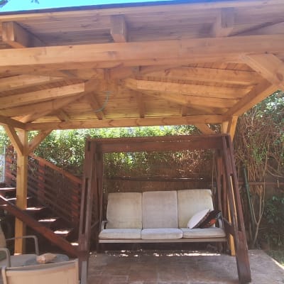 פרגולה מעץ עם נדנדה בגינה