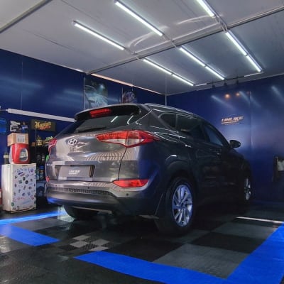 רכב בחדר שטיפה עם ציוד ניקוי על המדפים