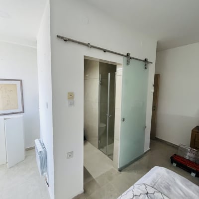 דלת זכוכית חלבית על מסילה בחדר אמבטיה