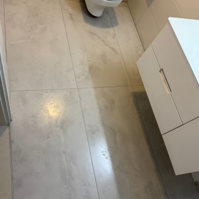 רצפת חדר אמבטיה עם אריחים חדשים, כיור ואסלה.