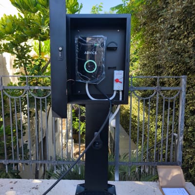 עמדת טעינה לרכב חשמלי מותקנת בחוץ ליד גדר
