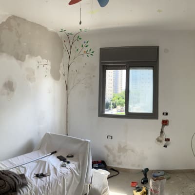 חדר בשיפוץ עם קירות מתוקנים וכלי עבודה על הרצפה