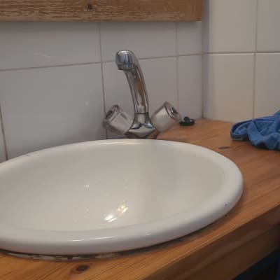 כיור עגול עם ברז מתכת על משטח עץ