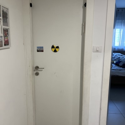 דלת לבנה עם ידית מתכת ושלט אזהרה