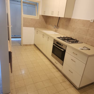 מטבח נקי עם ארונות לבנים וכיריים גז