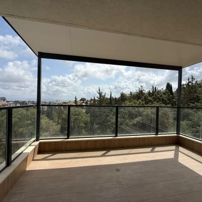 מרפסת עם פרגולה מאלומיניום ונוף לעצים