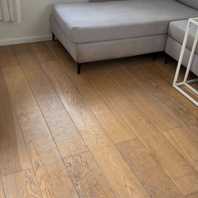 רצפת פרקט עץ ליד ספה אפורה בחדר מואר