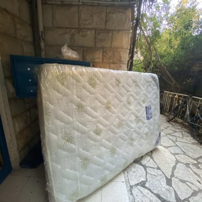 מזרן עטוף בפלסטיק בחצר עם אופניים ברקע