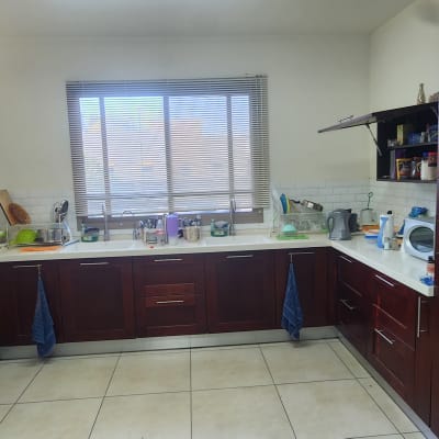 מטבח עם ארונות כהים ומשטחי עבודה לבנים