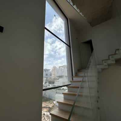מדרגות עץ עם מעקה זכוכית ליד חלון גדול