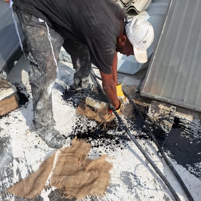 אדם מורח זפת על גג עם יריעות בד