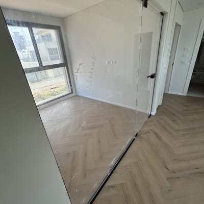 חדר עם רצפת פרקט ודלת זכוכית נקייה