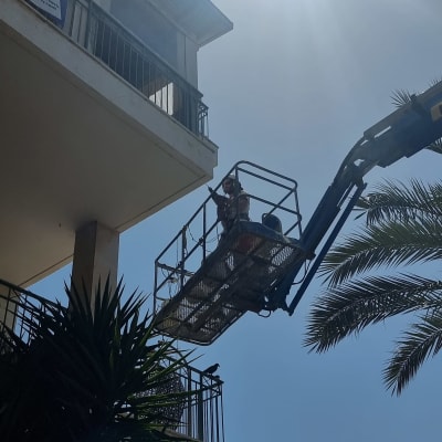 אדם על מנוף ליד בניין גבוה בשמש חזקה