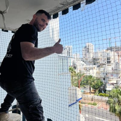 אדם מתקין רשת למניעת כניסת יונים במרפסת