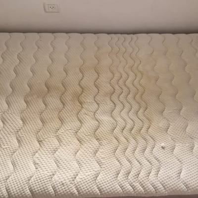 מזרן עם כתמים על רקע קיר לבן