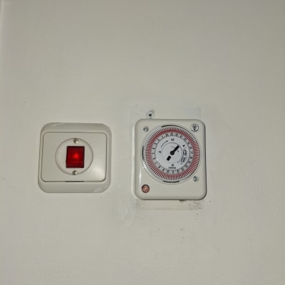 מתג חשמלי ושעון טיימר על קיר לבן