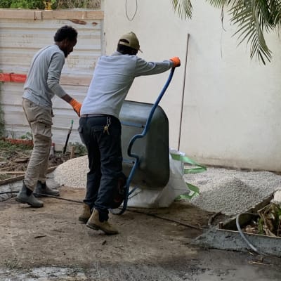 שני אנשים עובדים עם מריצה ליד ערימת חצץ
