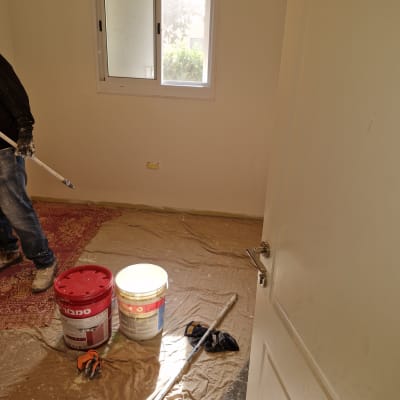 חדר עם דלי צבע, מברשת ורצפה מכוסה בניילון