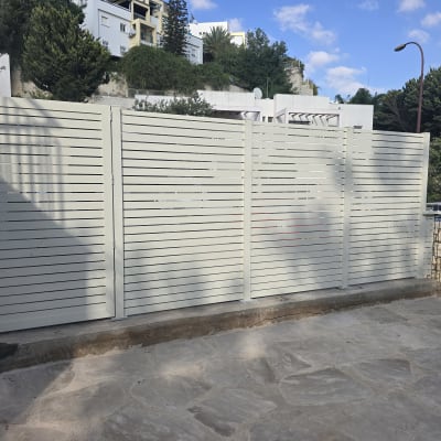 גדר אלומיניום לבנה בחצר עם רקע של עצים ובניינים