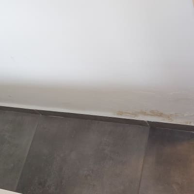 כתם רטיבות על קיר לבן ליד רצפה אפורה