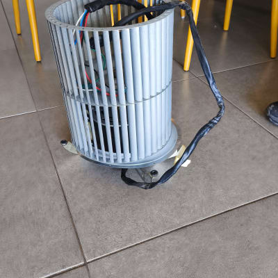 מאוורר מתכת על רצפה ליד כיסאות עץ