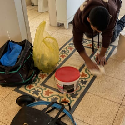 אדם מנקה רצפה עם כלים ליד שירותים