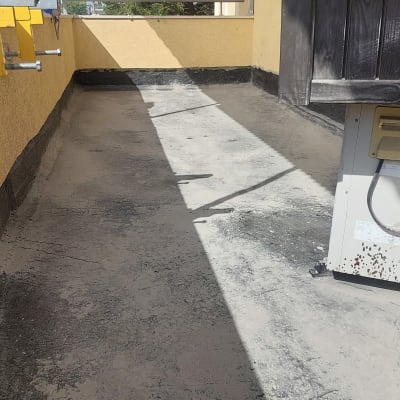 גג עם שכבת איטום כהה ליד קיר צהוב