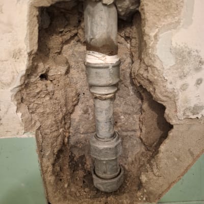 צינור חשוף בקיר עם טיח מתקלף