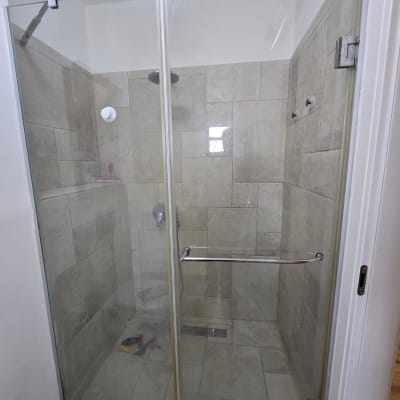 מקלחון זכוכית עם ראש מקלחת ומדף קטן