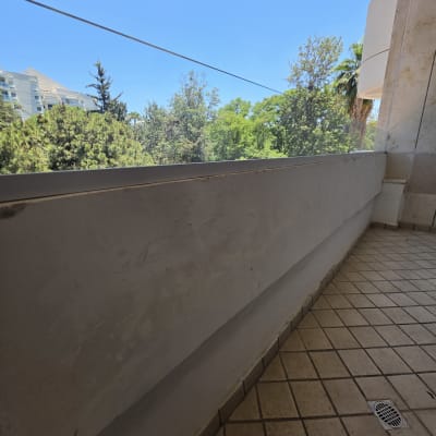 מרפסת עם מעקה זכוכית ונוף עצים