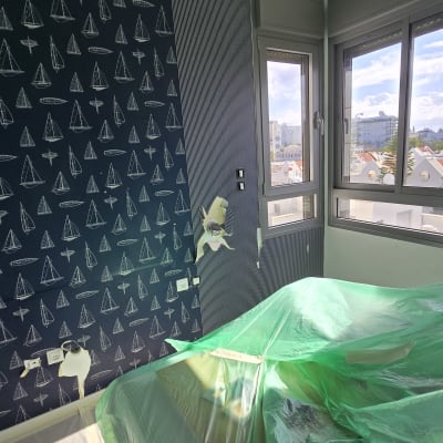 חדר עם קיר מעוצב בציורי סירות ויריעות פלסטיק ירוקות