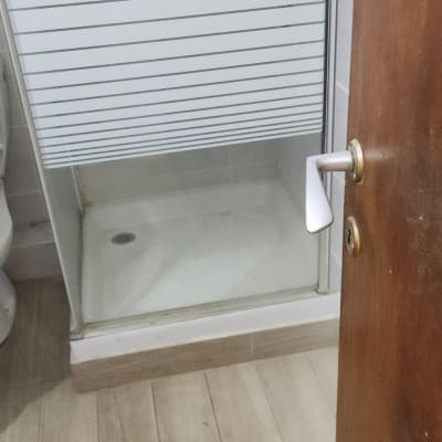 מקלחון זכוכית עם דלת פתוחה ורצפת עץ