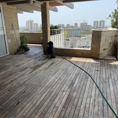 מרפסת עץ עם צינור מים ונוף עירוני ברקע