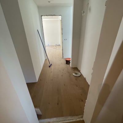 רצפת פרקט עץ עם מטאטא ודלי במסדרון