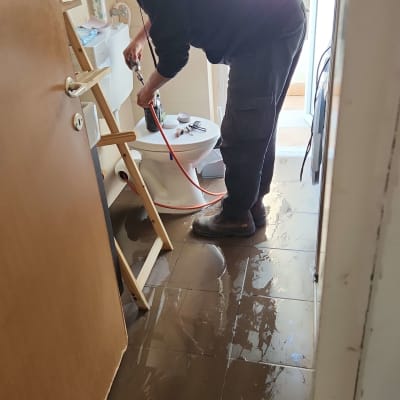 אדם עובד על תיקון שירותים עם כלים וצינור