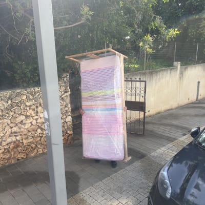 מזרן עטוף בניילון עומד בחוץ ליד רכב