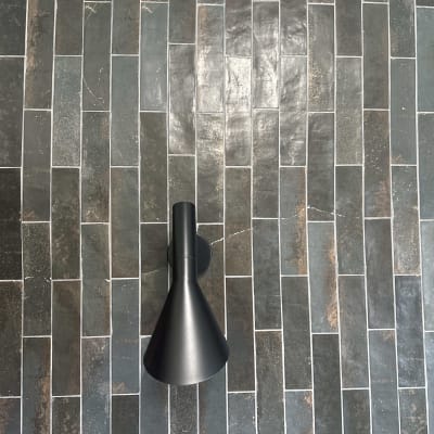 קיר אריחים כהים עם מנורת קיר שחורה