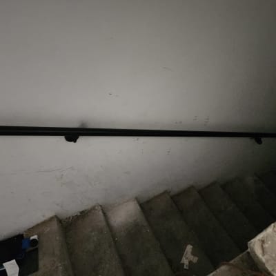 מעקה שחור מותקן על קיר מדרגות אפור