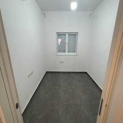 חדר ריק עם קירות לבנים ורצפת אריחים אפורה