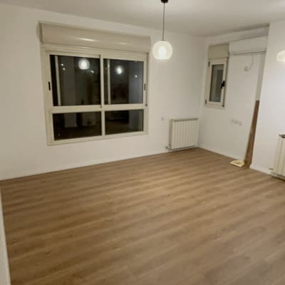 חדר עם רצפת פרקט, חלון ותאורה תלויה