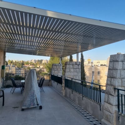 גג אלומיניום מעל מרפסת עם נוף עירוני