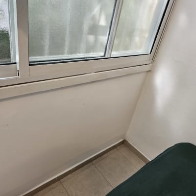 חלון זכוכית עם מסגרת לבנה על קיר לבן