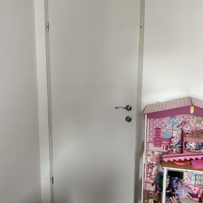 דלת לבנה עם ידית מתכת ליד בית בובות צבעוני