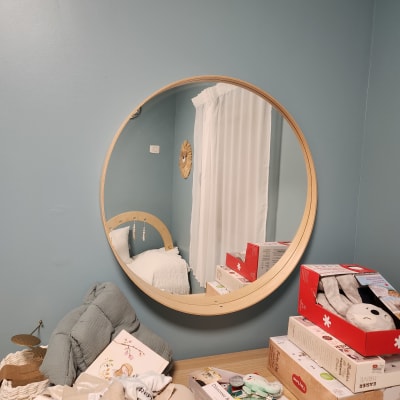 מראה עגולה תלויה על קיר כחול