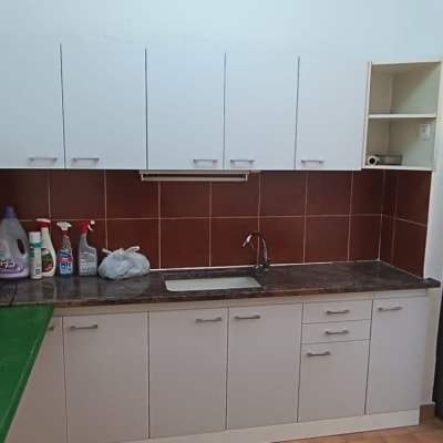 מטבח עם ארונות לבנים, כיור וברז, חומרי ניקוי