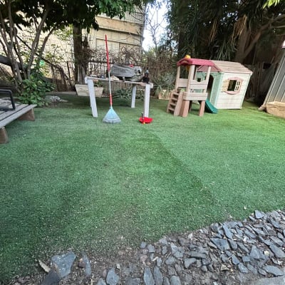 חצר עם דשא מלאכותי, מגרפה ובית משחקים לילדים